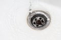 Close up a stream of clean water flows into the sink sewer hole. A jet of water flows into the drain enamel sink Royalty Free Stock Photo