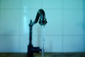 Close-up of a stream of water flowing from a black water tap in a kitchen in a retro style, blurred background, green backlighting Royalty Free Stock Photo