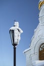 Close-up of a street lamp with a thick layer of frost on the glass. The lantern is located next to the church. The frost lying on