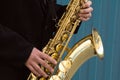 Close up of street saxophone Player hands playing alto sax musical instrument over blue background , closeup with copy