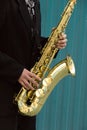 Close up of street saxophone Player hands playing alto sax musical instrument over blue background , closeup with copy Royalty Free Stock Photo