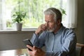 Close up stressed unhappy mature man looking at phone screen