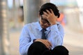 Close up of stressed young Asian businessman with hand on forehead sitting on floor. Feeling exhausted and headache against job.