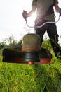 Close up of string grass cutting trimmer held by worker in protective clothing. Gardening concept Royalty Free Stock Photo