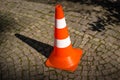 Close-up of striped orange and white road cone on pavement. Bright orange traffic cone for parking in the street. Royalty Free Stock Photo