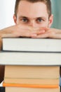 Close up of student hiding behind a pile of books