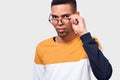 Close up studio horizontal portrait of handsome young African American man wearing and looking through round trendy spectacles.