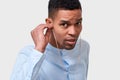 Close up studio portrait of candid dark-skinned man touching earphones, listens the music. Royalty Free Stock Photo