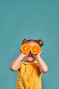 Close up studio portrait of child smiling holding halves of oranges at her eyes Royalty Free Stock Photo