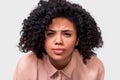 Close up studio portrait of displeased and questioned African American young womanr, looking serious at the camera