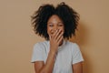 Beautiful dark skinned millennial woman covering her mouth with hand while laughing Royalty Free Stock Photo