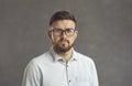 Close up studio portrait of millennial man with serious facial expression on gray background. Royalty Free Stock Photo