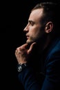 Studio portrait of young man in black shirt, holding hands in chin, looking down with humility. Royalty Free Stock Photo