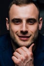 Studio portrait of young man in black shirt, holding hands in chin, looking down with humility. Royalty Free Stock Photo