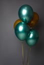 Close-up studio shot for advertising of colorful golden and metallic green inflated air balloons, isolated over gray background Royalty Free Stock Photo