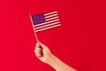 Close Up Studio Shot Of Female Hand Holding Stars And Stripes American Flag Against Red Background Royalty Free Stock Photo