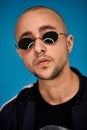 Studio shot of a young tattoed bald man posing against a blue background. 90s style. Royalty Free Stock Photo