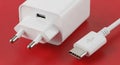 White USB- C Power Adapter and Charging Cable on a Red Background USB-C charger Royalty Free Stock Photo