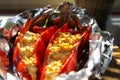 Close up of stuffed red paprika bell peppers with sheep feta cheese seasoned with spicy chili grilled in aluminium foil Royalty Free Stock Photo