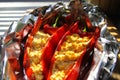 Close up of stuffed red paprika bell peppers with sheep feta cheese seasoned with spicy chili grilled in aluminium foil Royalty Free Stock Photo