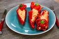 Close up of stuffed red paprika bell peppers with sheep feta cheese seasoned with spicy chili on wood table