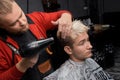 Close-up stylish bearded man european barber blow-drying hair to client guy before haircut in salon Royalty Free Stock Photo