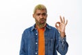 Close up of stylish hipster guy shows okay sign. Handsome african american man with yellow beard and hairstyle, makes ok Royalty Free Stock Photo