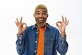 Close up of stylish hipster guy shows okay sign. Handsome african american man with yellow beard and hairstyle, makes ok Royalty Free Stock Photo