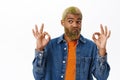 Close up of stylish hipster guy shows okay sign. Handsome african american man with yellow beard and hairstyle, makes ok Royalty Free Stock Photo