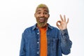 Close up of stylish hipster guy shows okay sign. Handsome african american man with yellow beard and hairstyle, makes ok Royalty Free Stock Photo