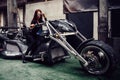 Stylish young woman model posing near a chic tricycle. Royalty Free Stock Photo