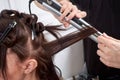 Close up of stylist`s hand using curling iron for hair curls Royalty Free Stock Photo