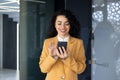 Close up of successful smiling hispanic woman using phone, businesswoman at workplace holding smartphone reading news Royalty Free Stock Photo