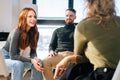 Close-up of successful young redhead businesswoman talking and discussing new ideas with creative business team Royalty Free Stock Photo