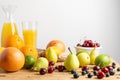 Close-up of summer fruits with bottle and glass with orange juice on wooden table, white background Royalty Free Stock Photo