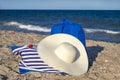Close-up of a summer straw hat, a striped bag and a blue backpack on a sandy beach. Travel and vacation concept Royalty Free Stock Photo