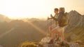 SUN FLARE: Young couple standing on the mountaintop and watching the sunset.