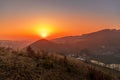 Close up sunset timelapse when sun is behind hills and mountains full of trees and moving clouds behind which sun sets a strong Royalty Free Stock Photo