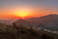 Close up sunset timelapse when sun is behind hills and mountains full of trees and moving clouds behind which sun sets a strong Royalty Free Stock Photo