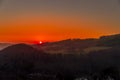 Close up sunset timelapse when sun is behind hills and mountains full of trees and moving clouds behind which sun sets a strong Royalty Free Stock Photo