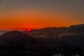 Close up sunset timelapse when sun is behind hills and mountains full of trees and moving clouds behind which sun sets a strong Royalty Free Stock Photo