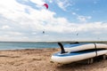 Close-up SUP board and kite equipment on sand beach shore watersport spot on bright sunny day against sea ocean coast