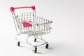 Close up of supermarket grocery push cart for shopping with black wheels and pink plastic elements on handle isolated on Royalty Free Stock Photo