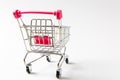 Close up of supermarket grocery push cart for shopping with black wheels and pink plastic elements on handle isolated on Royalty Free Stock Photo