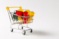 Close up of supermarket grocery push cart for shopping with yellow handle filled with multi-colored geometric shapes