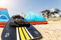 Close-up surf board and kite equipment on sand beach shore watersport spot on bright sunny day against rv camper van