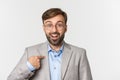 Close-up of surprised and excited office worker in glasses and gray suit, pointing finger at camera and looking amazed Royalty Free Stock Photo