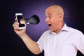 Close-up of a surprised, scared man holding a phone in his hand, from which a boxer strikes in a black boxing glove on a dark Royalty Free Stock Photo