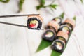 Close up of Sushi Roll piece with black rice and shrimp on top in metal chopsticks with blurred background. Royalty Free Stock Photo