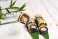 Close up of Sushi Roll piece with black rice and unagi eel on top in metal chopsticks with blurred background. Royalty Free Stock Photo